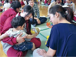 赤ちゃんを抱き、笑顔でふれあう高校生（松戸向陽高校で）の写真